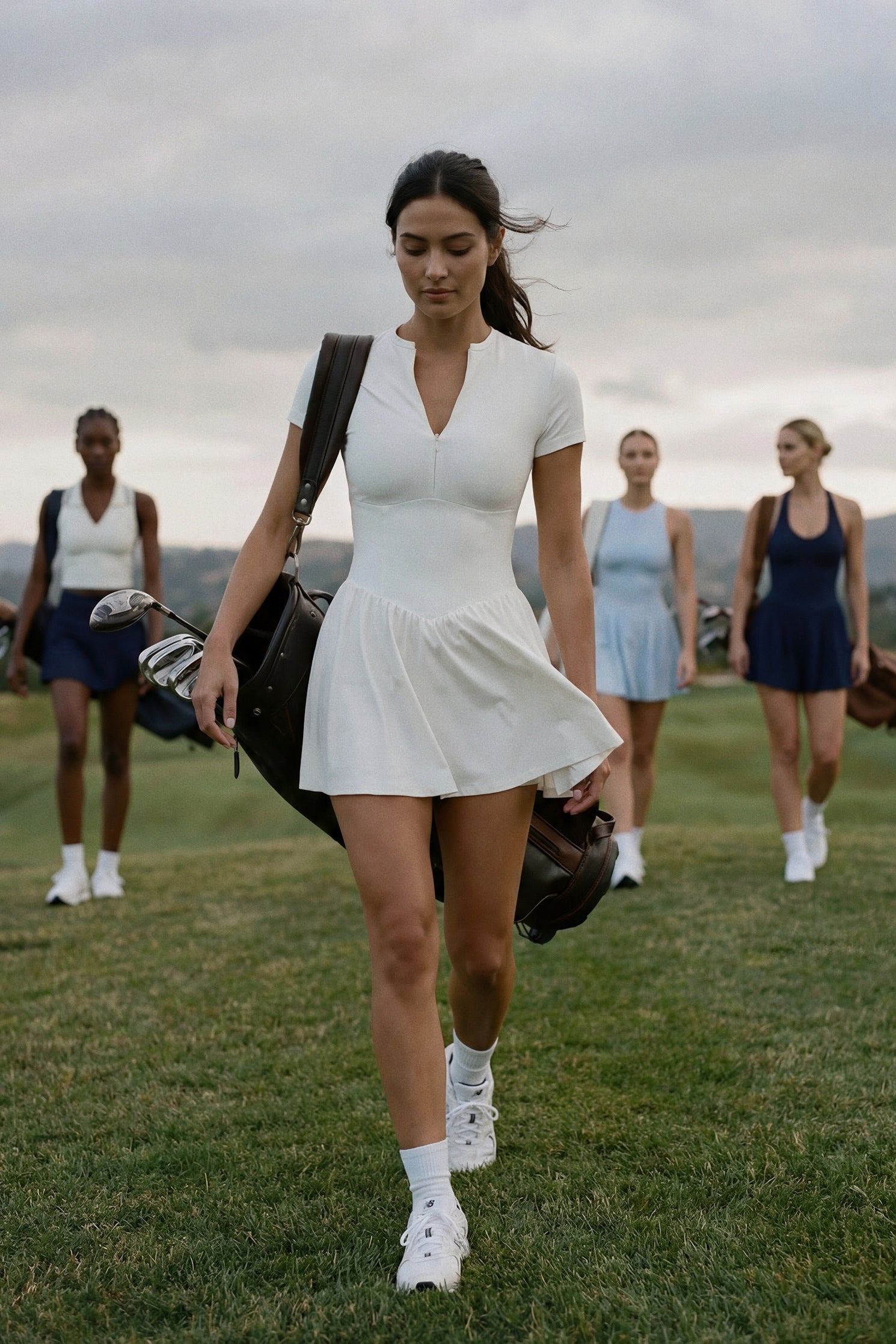 Woman in a white golf dress walking on a golf course with other people in the background
