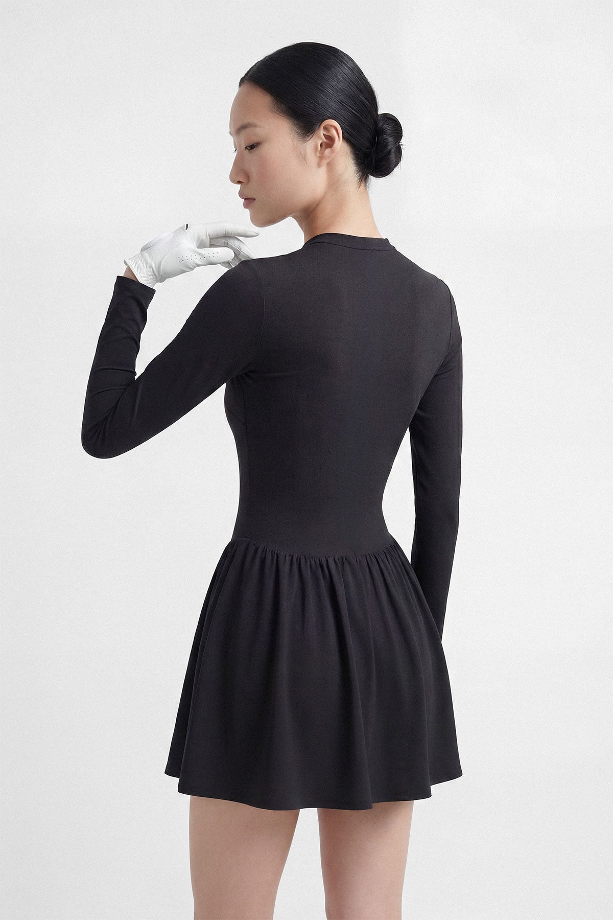 A black long sleeve golf dress with a zipper closure, built-in shorts and a side pocket