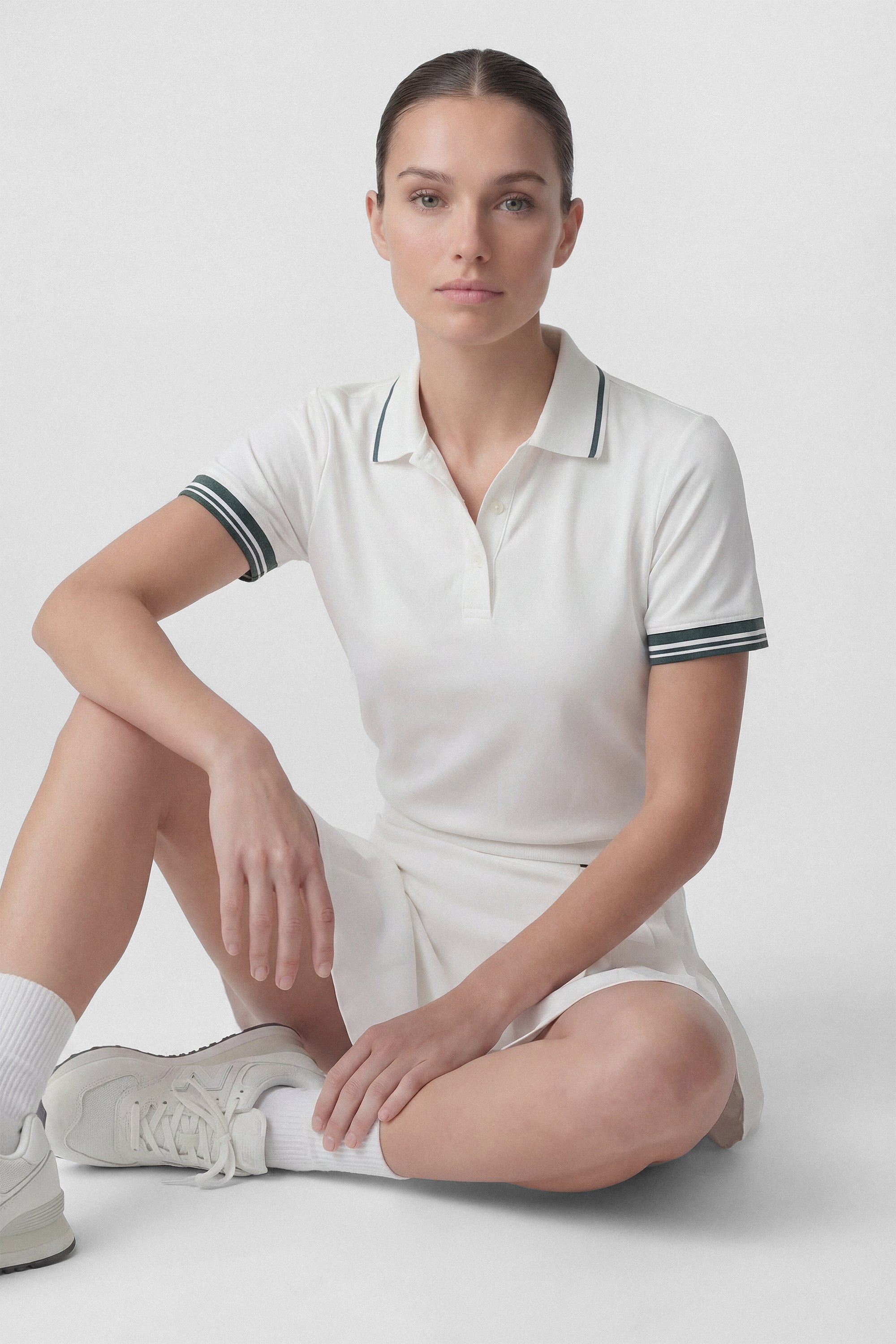 Model wearing a white golf polo top with green stripes