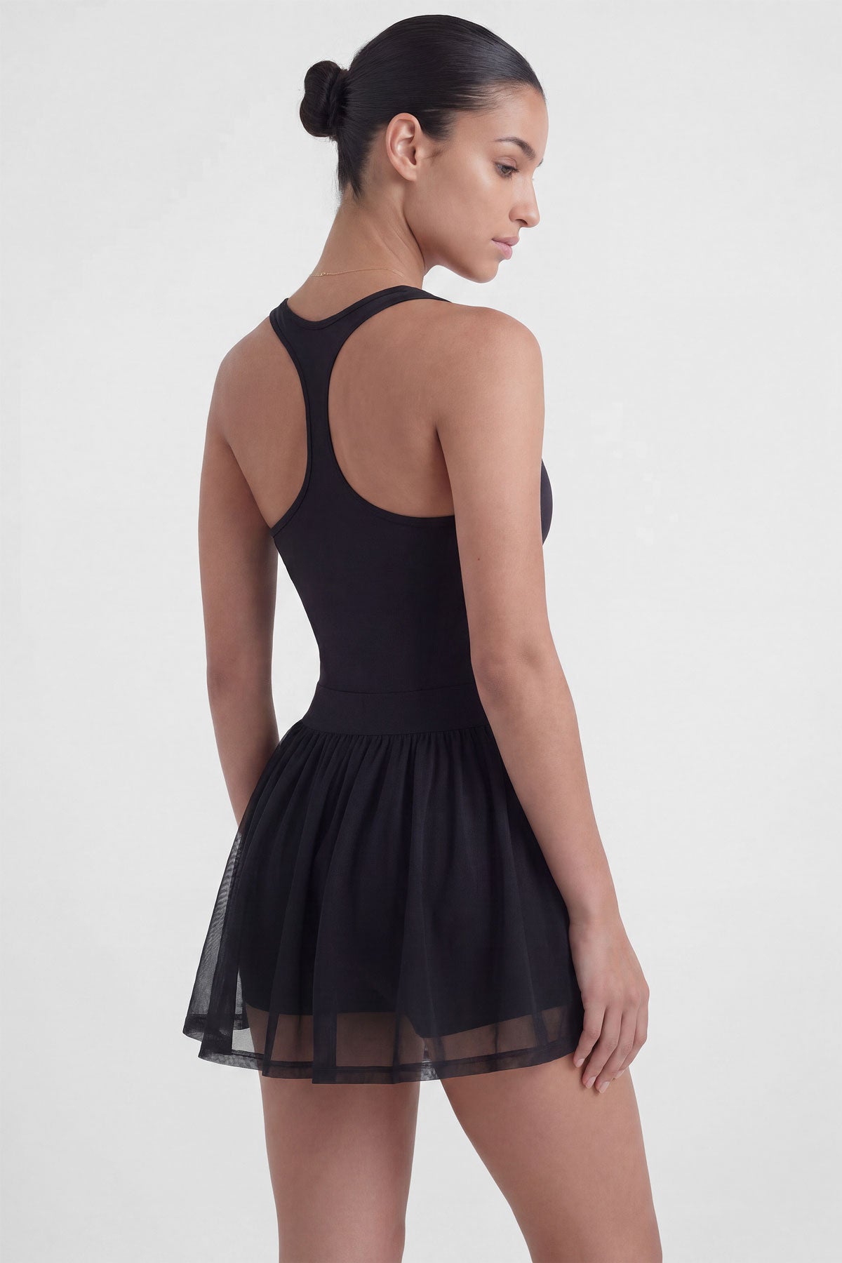 Black tennis dress with square neckline, racerback, sculpting bodice, and sheer mesh skirt with built-in shorts