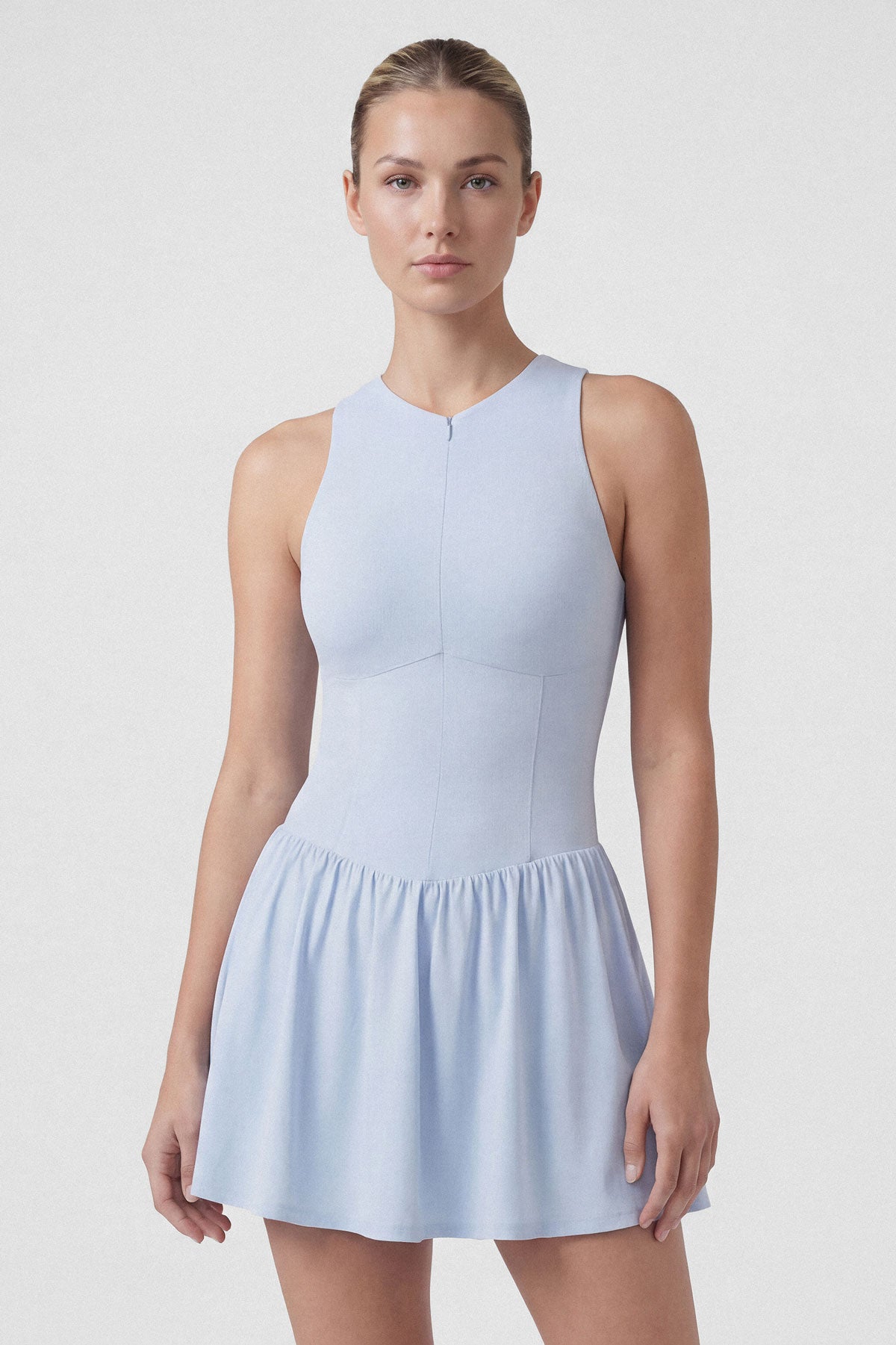 Woman tennis player wearing a light blue sleeveless tennis dress with built-in shorts