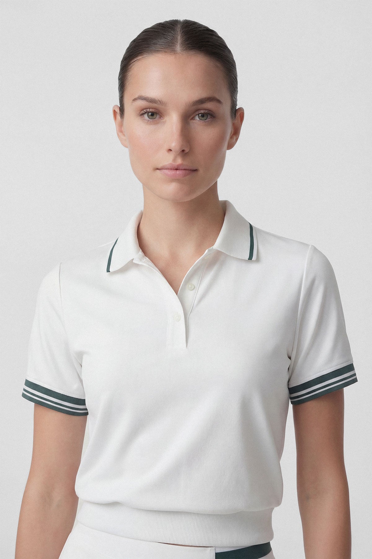 A white women's golf polo top with dark green stripes on the collar and sleeves