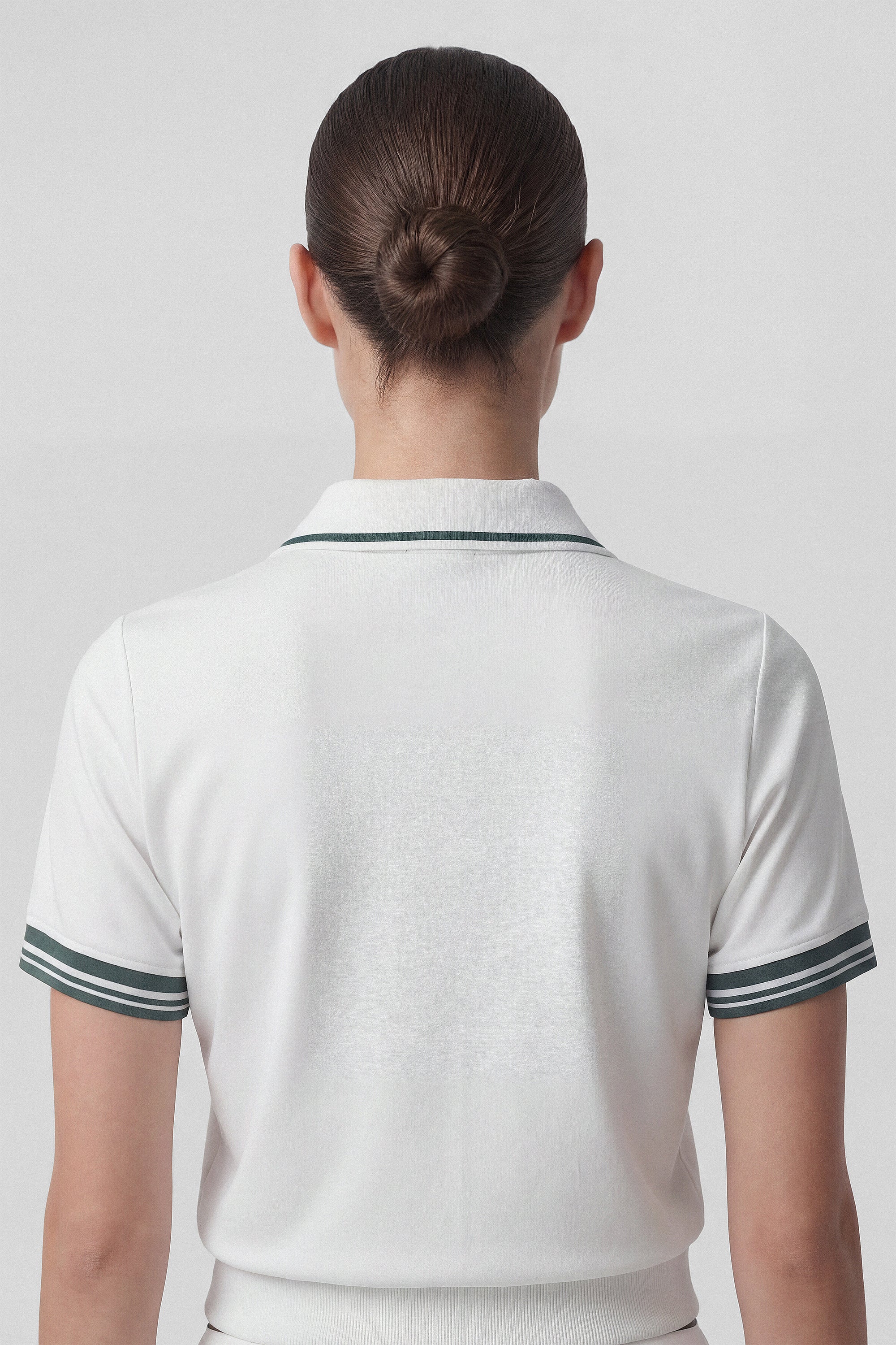 Model wearing a white golf polo top with green stripes