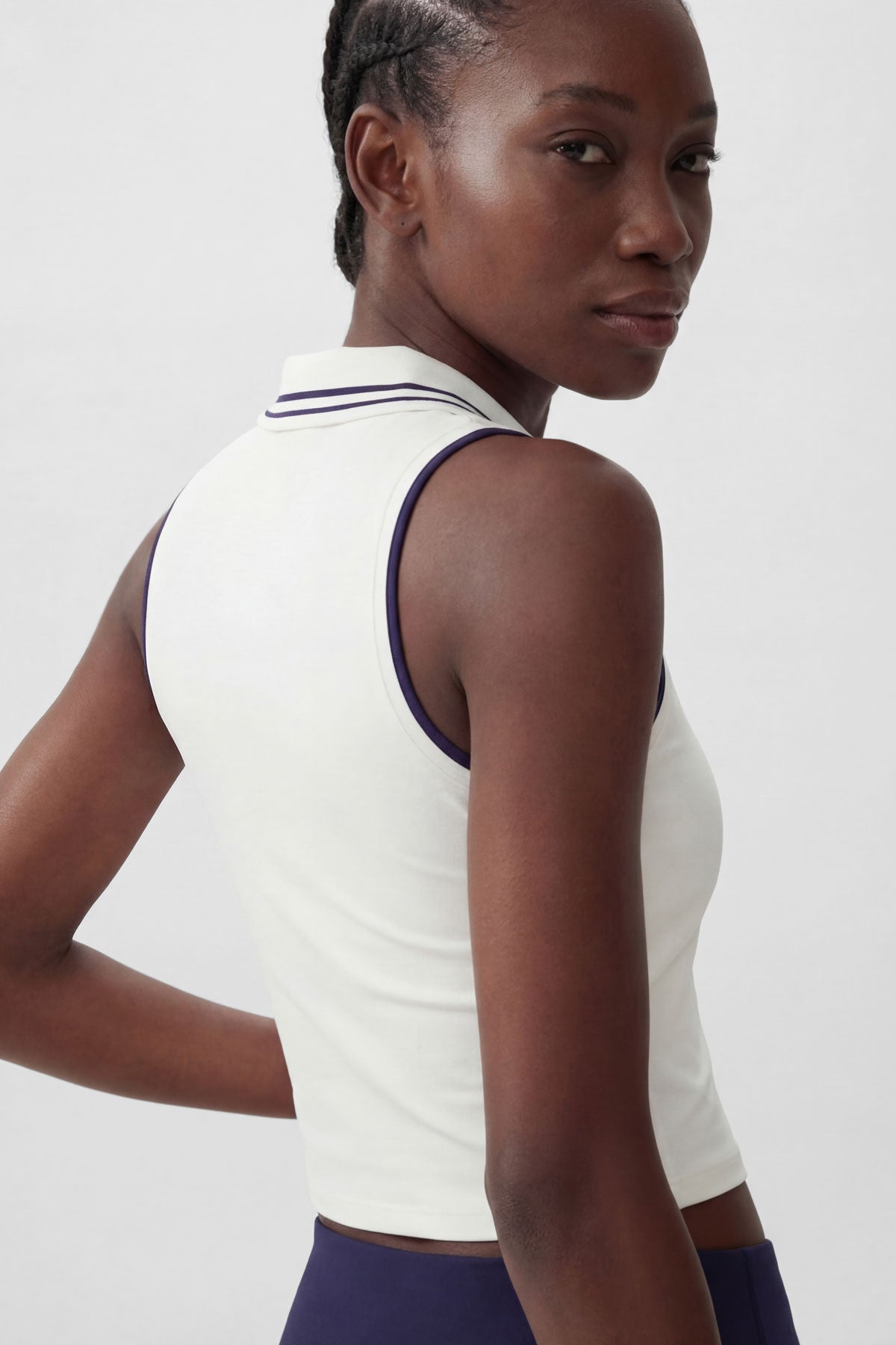 A white cropped collared polo top with navy stripe accents and built-in bra