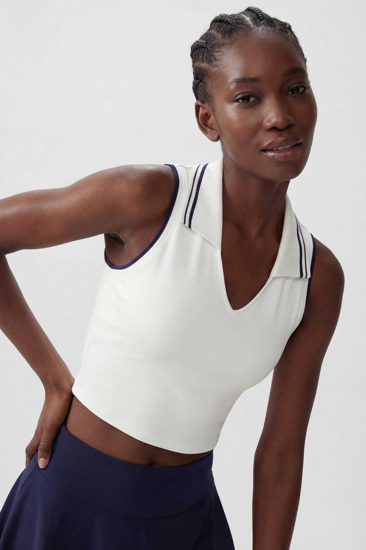 A white cropped collared polo top with navy stripe accents and built-in bra