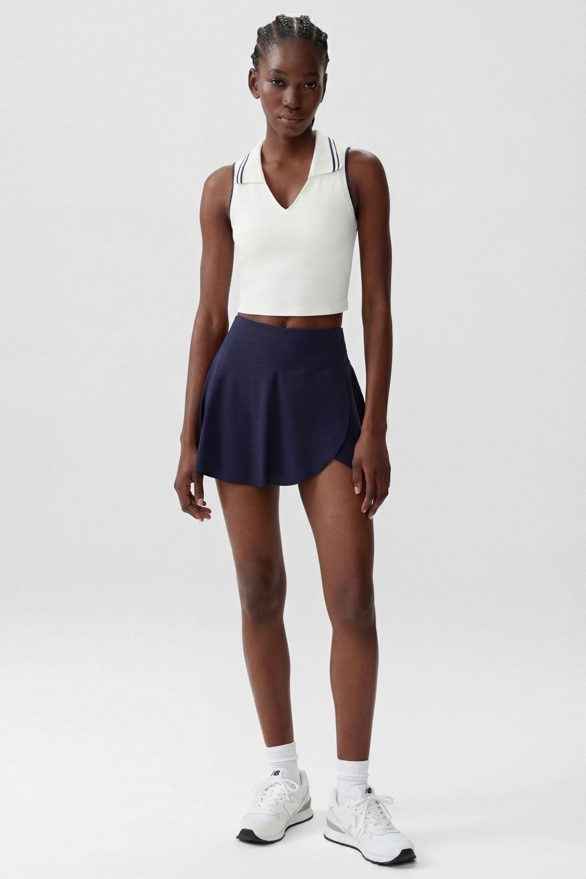A white cropped collared polo top with navy stripe accents and built-in bra