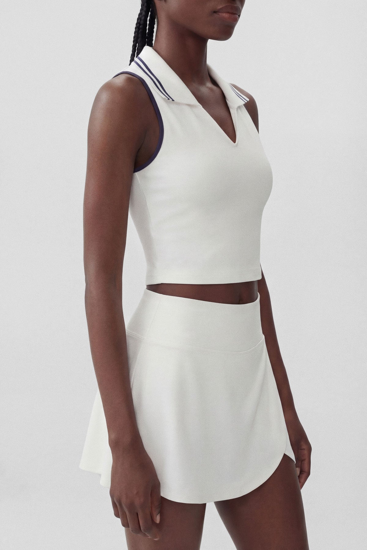 A white cropped collared polo top with navy stripe accents and built-in bra
