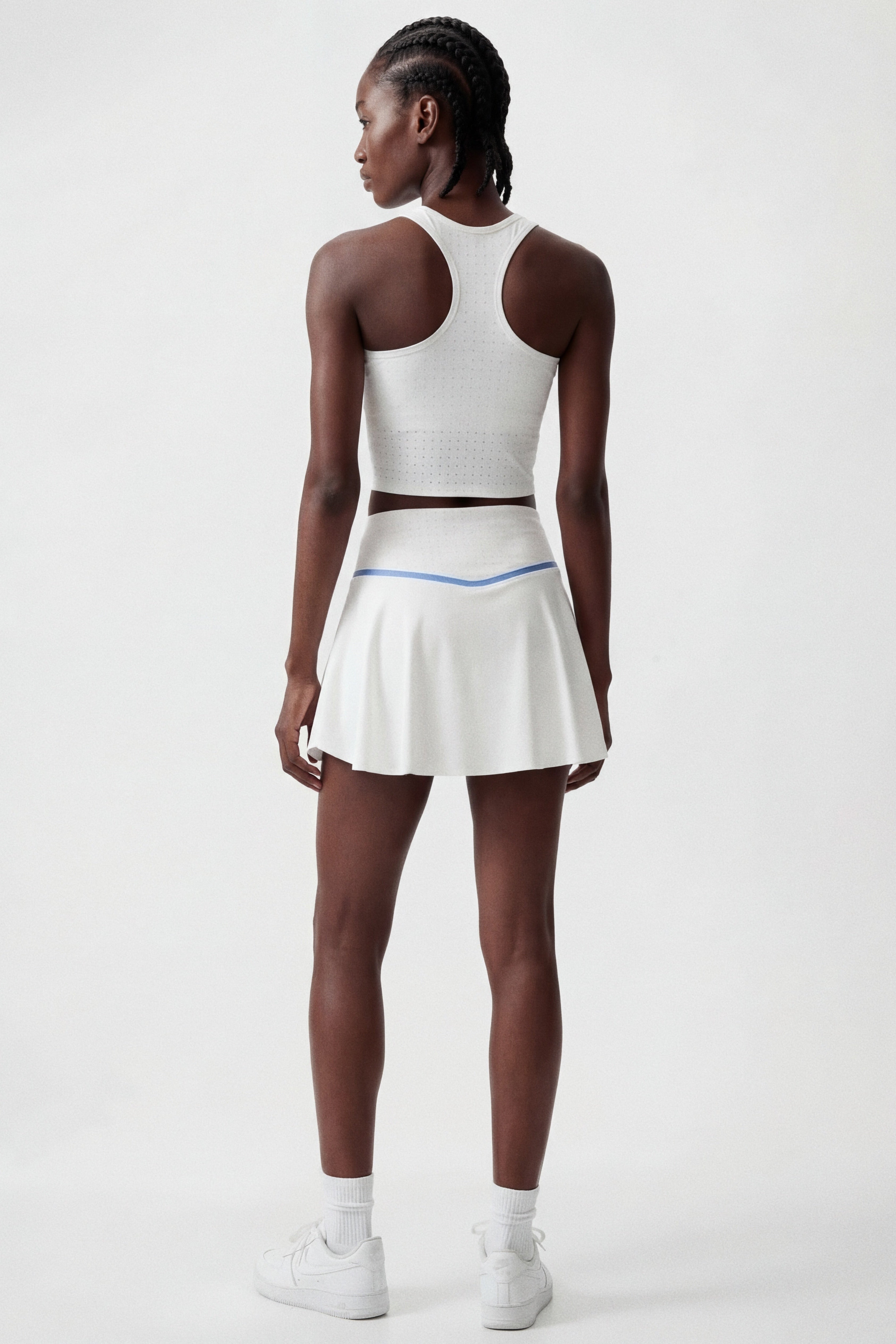 Woman wearing a white tennis crop top and white tennis skirt