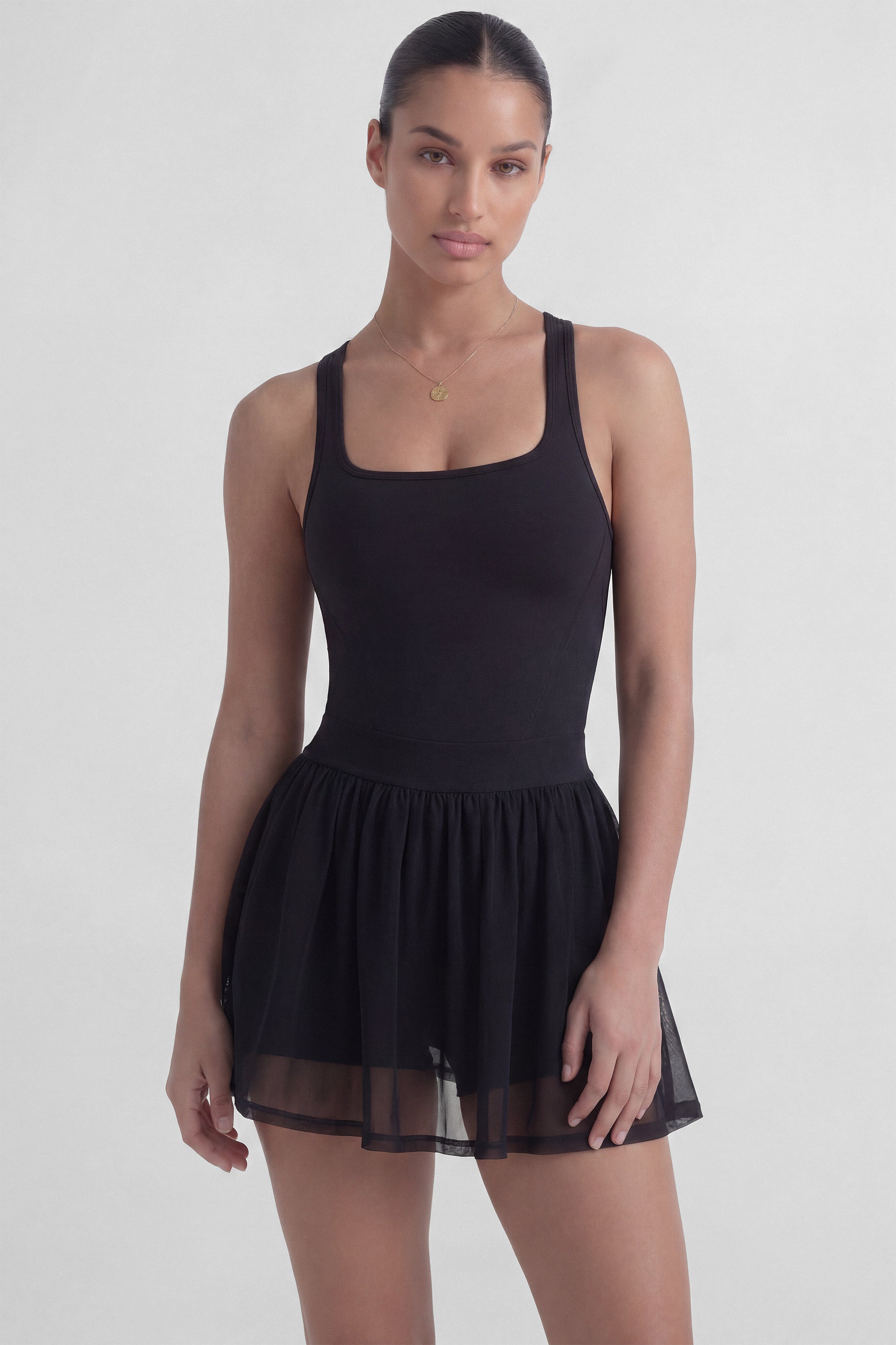 Black tennis dress with square neckline, racerback, sculpting bodice, and sheer mesh skirt with built-in shorts from Common Player