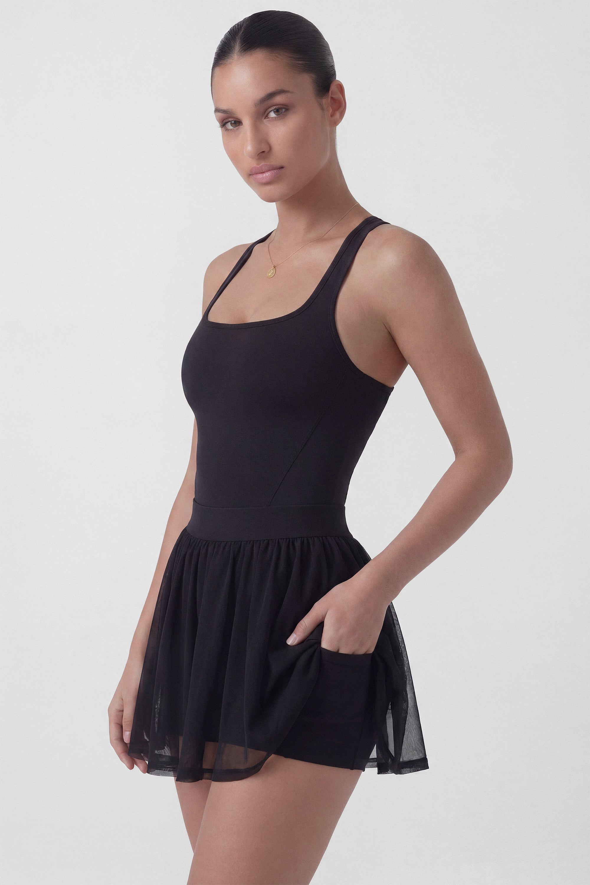 Black tennis dress with square neckline, racerback, sculpting bodice, and sheer mesh skirt with built-in shorts from Common Player