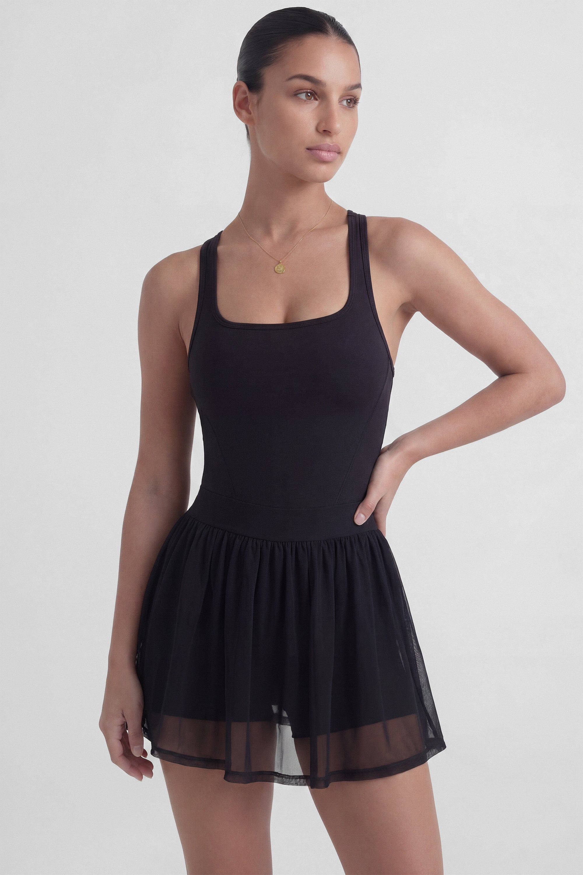Black tennis dress with square neckline, racerback, sculpting bodice, and sheer mesh skirt with built-in shorts from Common Player