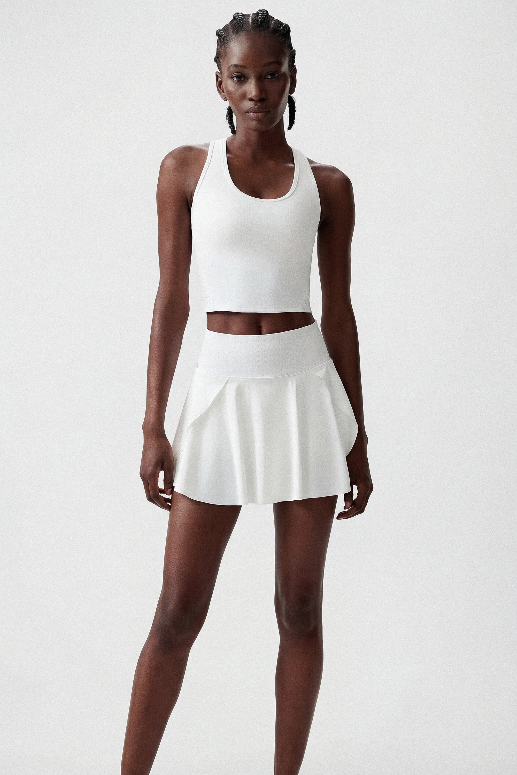 Woman wearing a white tennis crop top and white tennis skirt